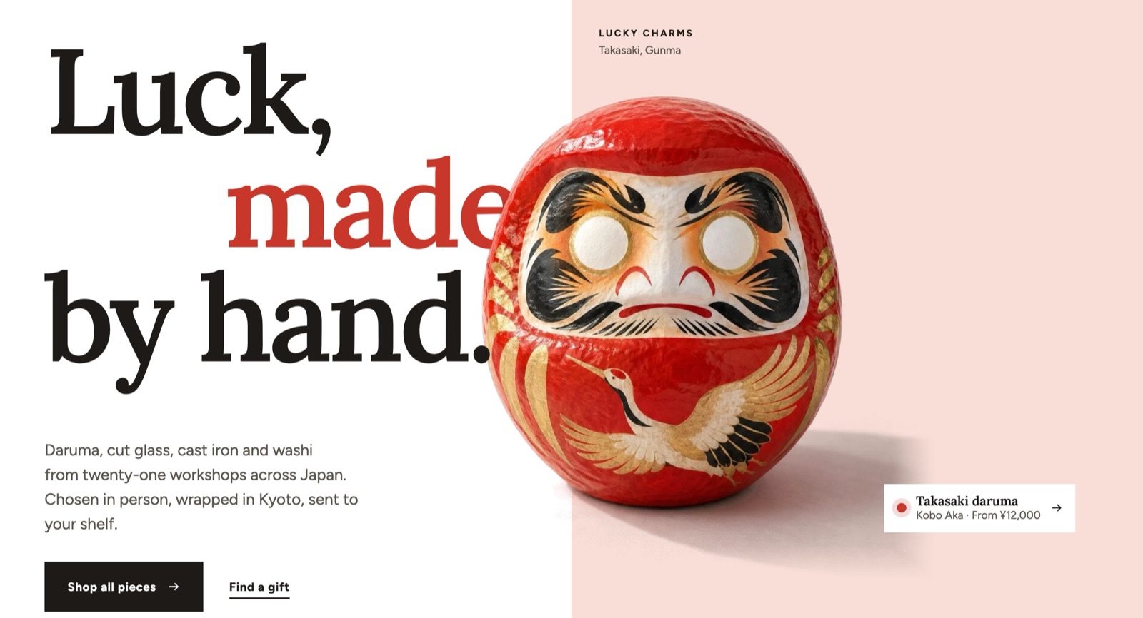 The Interlocking hero: the headline “Luck, made by hand.” and a red daruma on a pale pink field